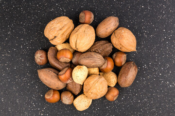 Pile of assorted nuts in the shell isolated over black top down view