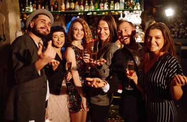 Happy friends throwing confetti and jumping while enjoying party. Group of  young people celebrating together winter holiday. Confetti is fun. Party, celebration, drink, birthday concept.