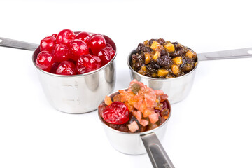 Silver measuring cups containing maraschino cherries, mincemeat, and fruit cake mix