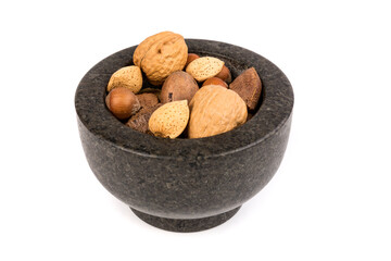 Pile of assorted nuts in the shell in a mortar bowl isolated over white