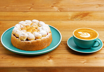 Homemade cherry pie with almond petals and cup of coffee cappuccino on wooden table.