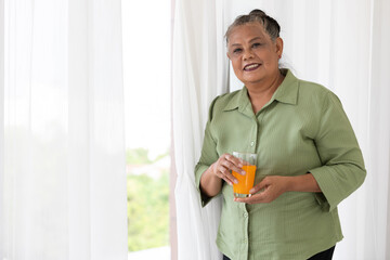portrait senior woman smiling and holding a glass of orange juice