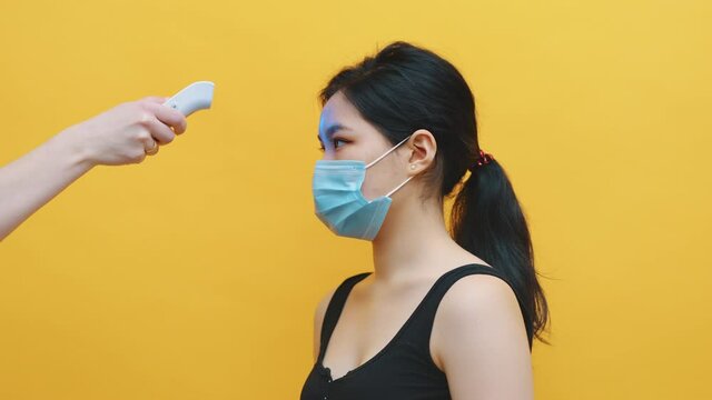 Health-care worker, doctor checks temperature of young asian woman. Medical test for coronavirus diagnosis in hospital during pandemic. Healthcare and medicine concept. High quality 4k footage