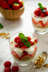 Glasse with layered yogurt, granolla and fruits, strawberry ans raspberry. Healthy breakfast.