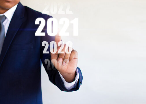 Businessman, indexing finger, searching for 2021 numbers on a computer screen: new year start ideas