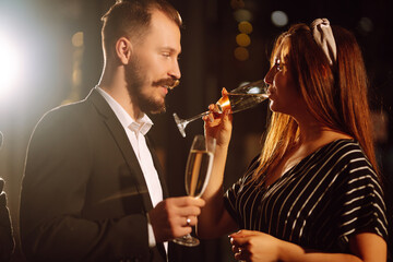 Young happy couple in love toasting with champagne on the bar. Smiling man and woman clinking a glass champagne, enjoying winter holiday. Party, celebration, drink, birthday concept.