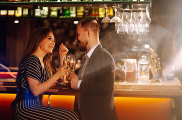 Young happy couple in love toasting with champagne on the bar. Smiling man and woman clinking a...