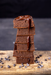 Cocoa brownies pouring with melted dark chocolate on a white plate. Black background