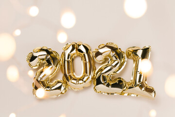 Gold foil balloons numeral 2021, party decoration on beige and Set Sail Champagne background. Flat lay, christmas creative concept