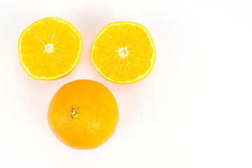 An overhead view of one unpeeled tangerine and the other cut into two equal halves. Isolated over white background.