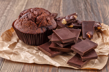 Chocolate cupcake with icing and chocolate bar in Dark lighting,Homemade delicious chocolate muffin on wooden background close-up