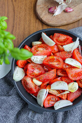 Sliced tomatoes, garlic and onion on oven pan ready to be roasted. Tomatoes seasoned with spices and olive oil. 
