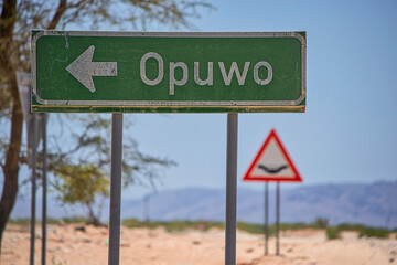 Green directional road sign to the city of Opuwo in Namibia, Africa.
