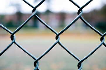 Geometrical grey-green wire fence in close-up at tennis court