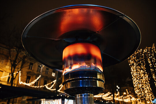 Closeup Shot Of A Gas-burning Outdoor Patio Heater With Christmas Lights In The Background