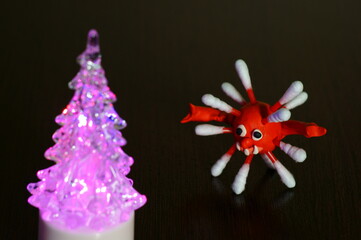 Figures of multi-colored viruses on the table. There is a small Christmas tree nearby.