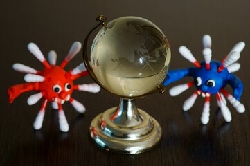 Figures of multi-colored viruses on the table. Next to it is a small glass globe.