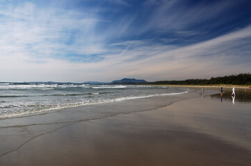 Beachcombers on the flat shore of long beach