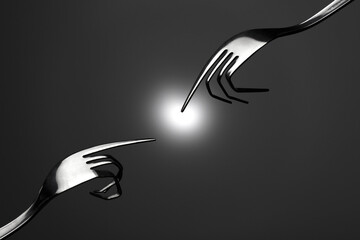 Closeup of metal forks with bent tines shaped like fingers touching a bright ight