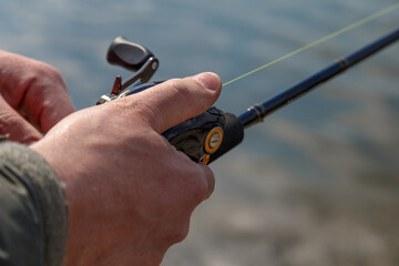 hand with spinning and reel on the evening summer lake. Fishing on the lake at sunset. Fishing...