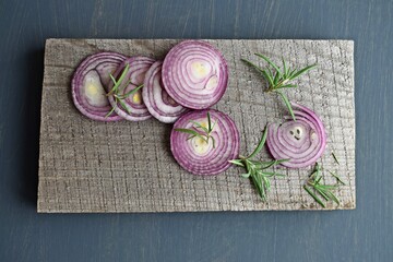 Red sliced onion and rosemary on a wooden background.
