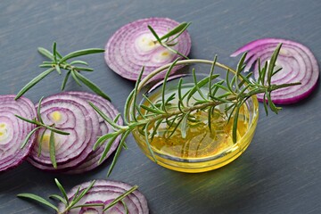 Red sliced onion and rosemary on a wooden background.