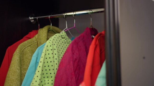 woman opens wardrobe and takes clothes at home, choice of clothes