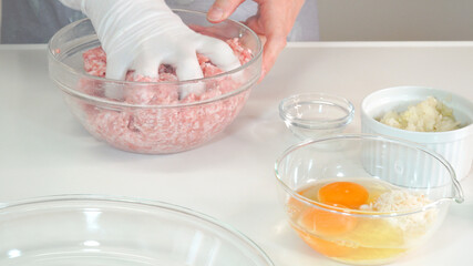 挽き肉に塩胡椒を混ぜてこねる主婦　料理シーン