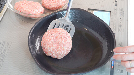 ハンバーグの種をフライ返しでフライパンに置く様子