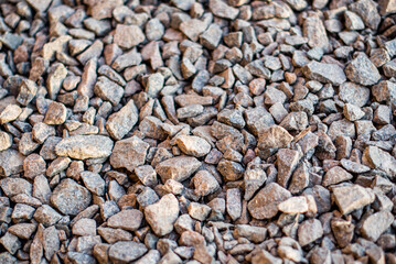 Gravel texture. Small stones, little rocks, pebbles in many shades of grey, white, brown, yellow colour. Background of small wet stones in oval shape. Texture of little rocks from river or lake.