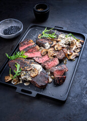 Modern style barbecue dry aged wagyu Brazilian picanha steaks from the sirloin cap of rump beef sliced and served cream sauce and mushrooms as close-up on a design tray
