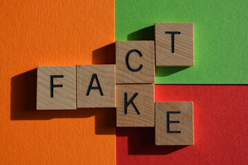Fact, Fake, words in wooden alphabet letters on red, orange and green background