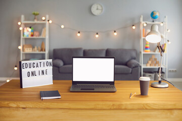 Online education sign and laptop computer with empty screen standing on wooden table in living room, mockup for design