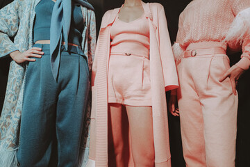 Three cropped female figures in pink and blue stylish elegant clothes on backstage Fashion week