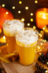 Pumpkin spice latte in a glass mug with cinnamon and whipped cream. Bokeh background. Autumn, winter drinks. Holiday drinks. Christmas drink.