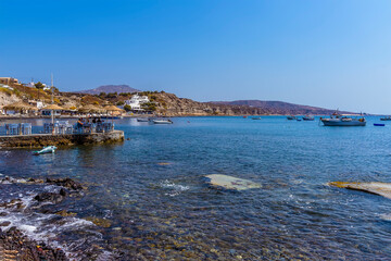 Fototapeta premium A view across the bay close to the Red Beach in Santorini towards a water side cafe in summertime
