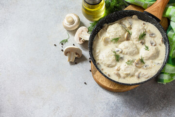 Homemade meatballs in sour cream sauce with mushrooms in a pan on stone or slate table. Copy space.
