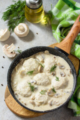 Homemade meatballs in sour cream sauce with mushrooms in a pan on stone or slate table.