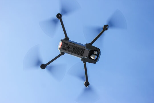 Looking down at a remote controlled quadcopter drone while in flight on a sunny day.