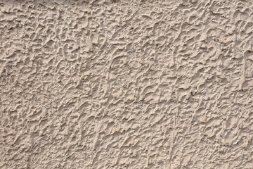 Fragment of a three-dimensional large-relief texture of textured plaster on the exterior of the Foundation of a house outdoor.