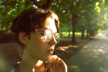 Portrait of a cute charming brunette with a short haircut and transparent glasses. A young woman...