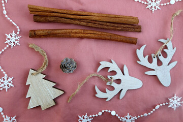 Various Christmas decorations and cinnamon sticks on pink background. Top view.