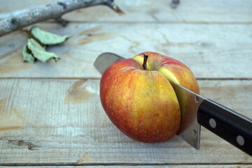 cut red apple with a knife on a wooden table