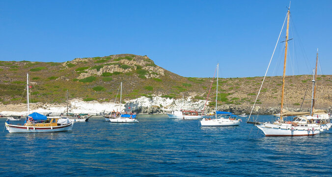 Boats and yachts are parked at the bay. People are swimming in the turquoise water of Mediterranean Sea, Turkey. Lots of yachts in the frame.