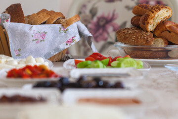 Side view of Turkish breakfast with lots of dish on the table. Tomato, cucumber, cheese, sauce, bagel, bread and pastry on the table.
