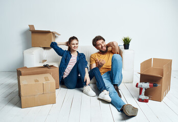 Fototapeta na wymiar Emotional man and woman with cardboard boxes on the floor having fun moving renovation work