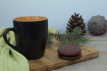 
mug round cookies and pine cone of a christmas tree on a wooden table