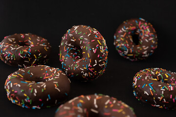 Delicious Chocolate Donuts with colorful sprinkles, Black background