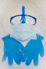 Personal protective equipment during the coronavirus epidemic - goggles, a disposable medical mask, disposable nitrile gloves, a bottle of antiseptic - on the table.