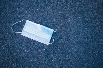 Protective medical mask on the asphalt. Epidemic second wave concept.